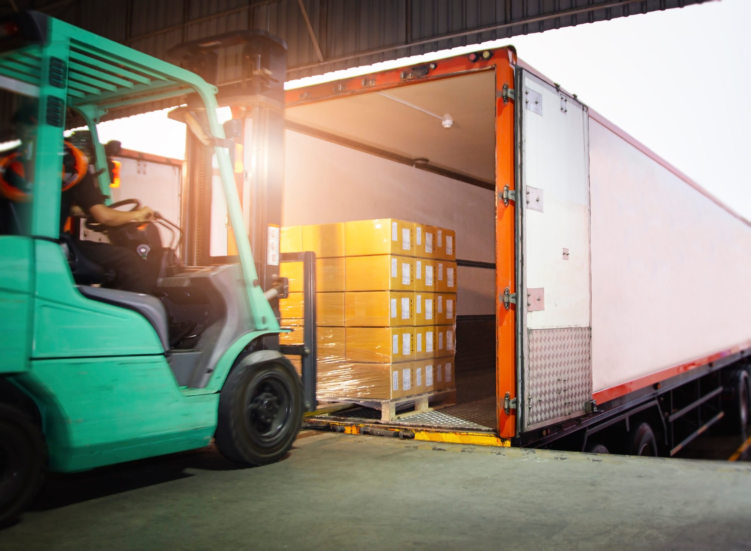 Employee drives loading vehicle to shipping container to highlight Vortex SAP logistics and distribution experience.